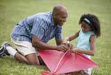 Man helping his daughter to fix a kite