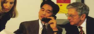 Man on phone next to two business colleagues
