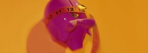 Measuring tape around piggy bank 