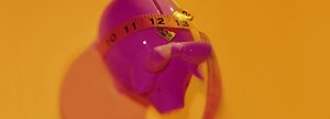 Measuring tape around piggy bank 
