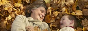 Grandmother and grandson laughing in fall leaves