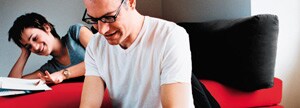 Couple at home reading and working on a laptop