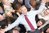Man in tie being lifted by co-workers