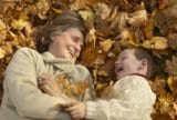 Grandmother and grandson laughing in fall leaves