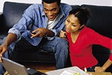Couple sitting on couch looking at laptop