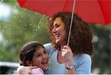 Mother and daughter smiling under umbrella