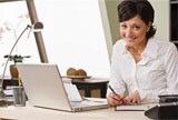 Woman writing a cheque in front of her computer