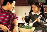 Man on phone while making dinner with daughter