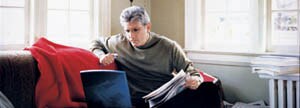 Un homme avec son journal devant son portable.