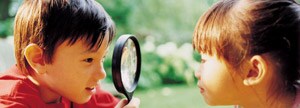 Deux enfants regardent à travers une loupe