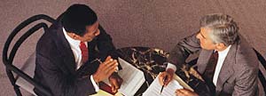 Two businessmen in office reading newspaper