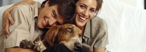 Pareja sonriendo al lado de su mascota