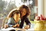 Little girl doing her homework with her mother