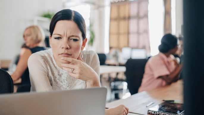 Someone looking at a laptop with a quizzical look