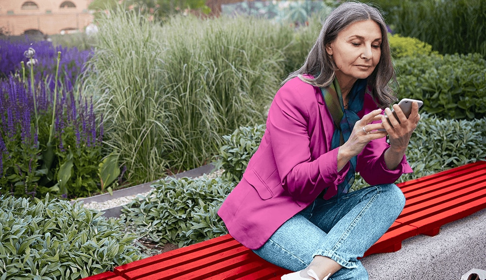 Femmes assises sur un banc de jardin sur son iphone.