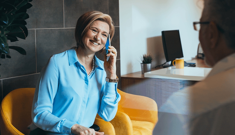 Women sitting in yellow chair talking on her iPhone.