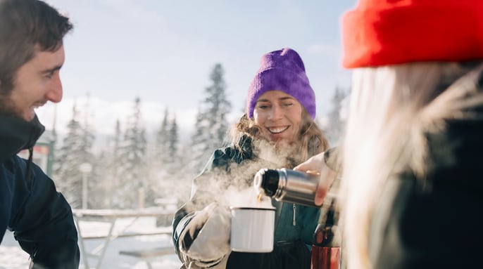 Trois amis partageant un café en plein air en hiver