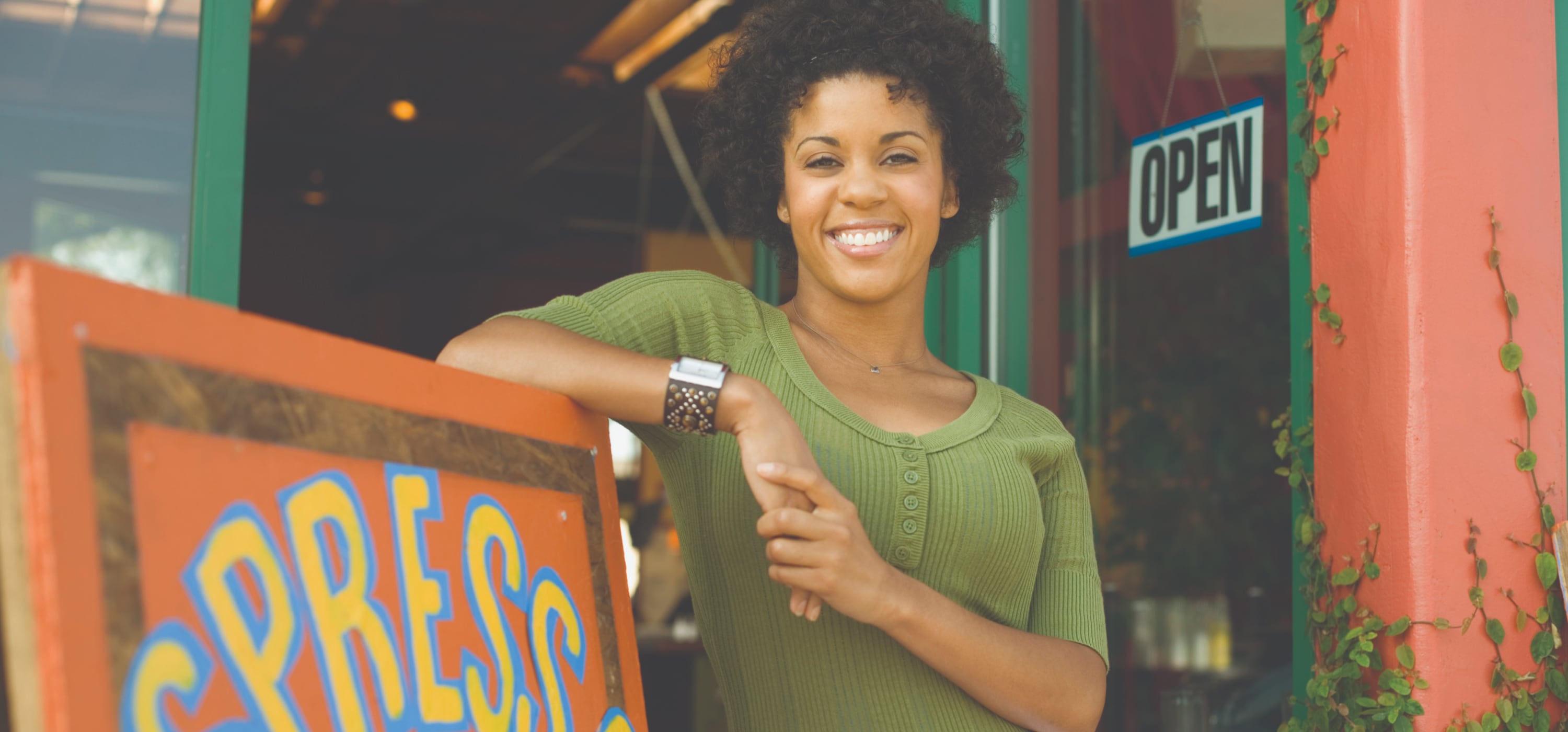 Black woman leaning against a shop sign 