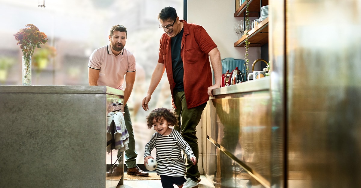 Two men watch child running playfully