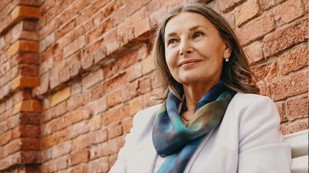 A female wealth client sitting outdoor, smiling.