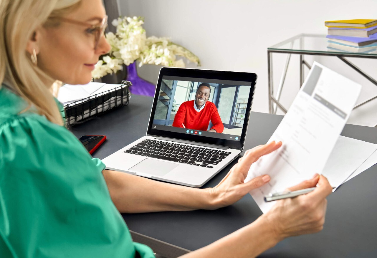 Woman infront of laptop with man on screen
