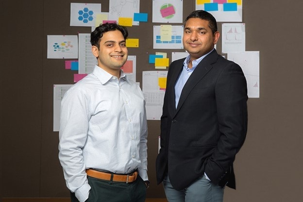 Dr. Verma and Dr. Razak posing in front of board containing notes