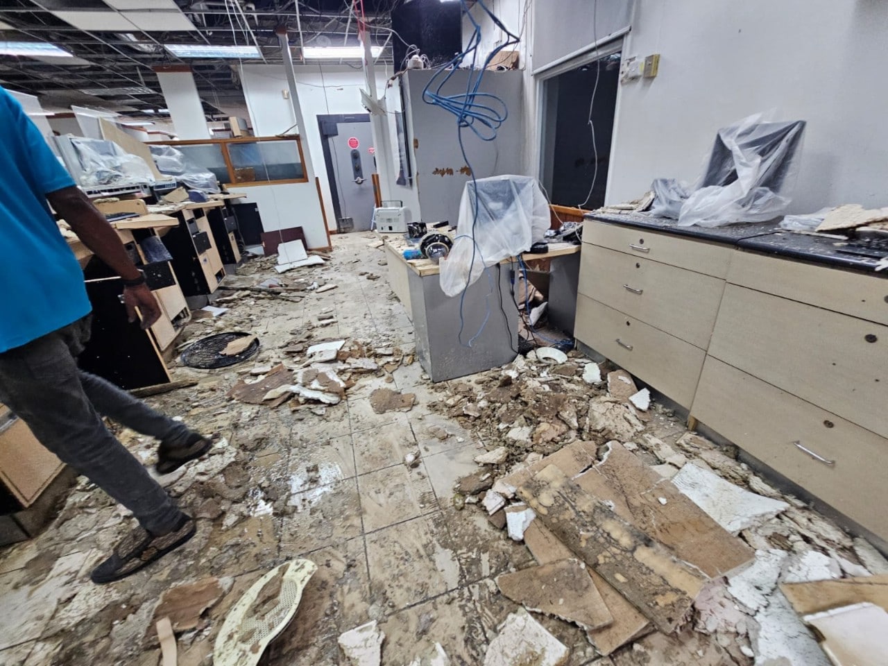 Inside of bank branch with debris littering floor and wires hanging from damaged ceiling