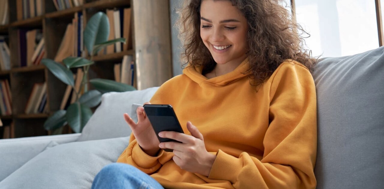 Someone looking down at their device and smiling  